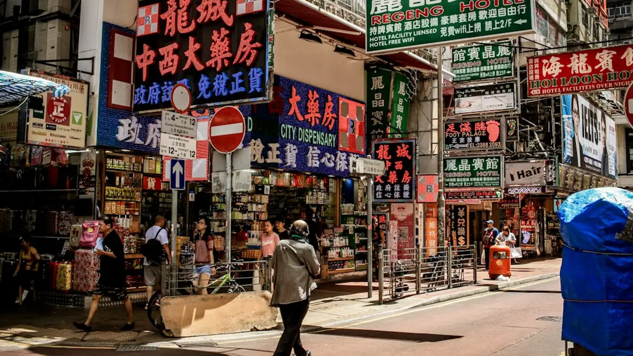香港街頭的藥房與商店招牌林立，招牌上寫著「中西大藥房」「大藥房 CITY DISPENSARY」，行人從藥房門口走過