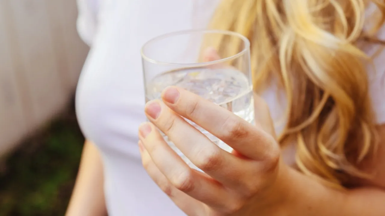 一名女性雙手捧著一杯水，畫面只取到上半身